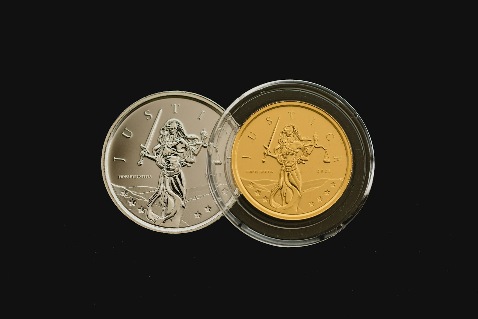 Gold and silver Lady Justice coins on a dark background